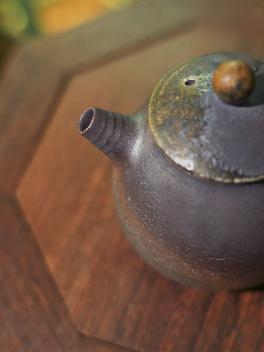 Close-up of the rugged, grainy mineral surface of a handmade iron-rich clay teapot.