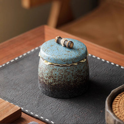 Minimalist setup featuring a gilded vintage Chinese stoneware tea caddy on a wooden table.
