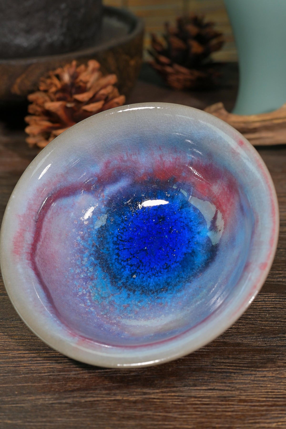 Handcrafted 100ml wood-fired tea bowl featuring elevated pedestal foot and dramatic blue-purple glaze streaks