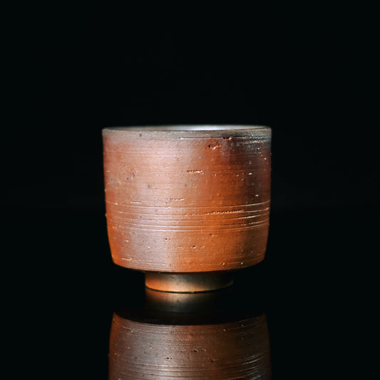 Wood-fired coarse clay master cup with granular texture and natural ash deposits from 1300°C+ naked firing