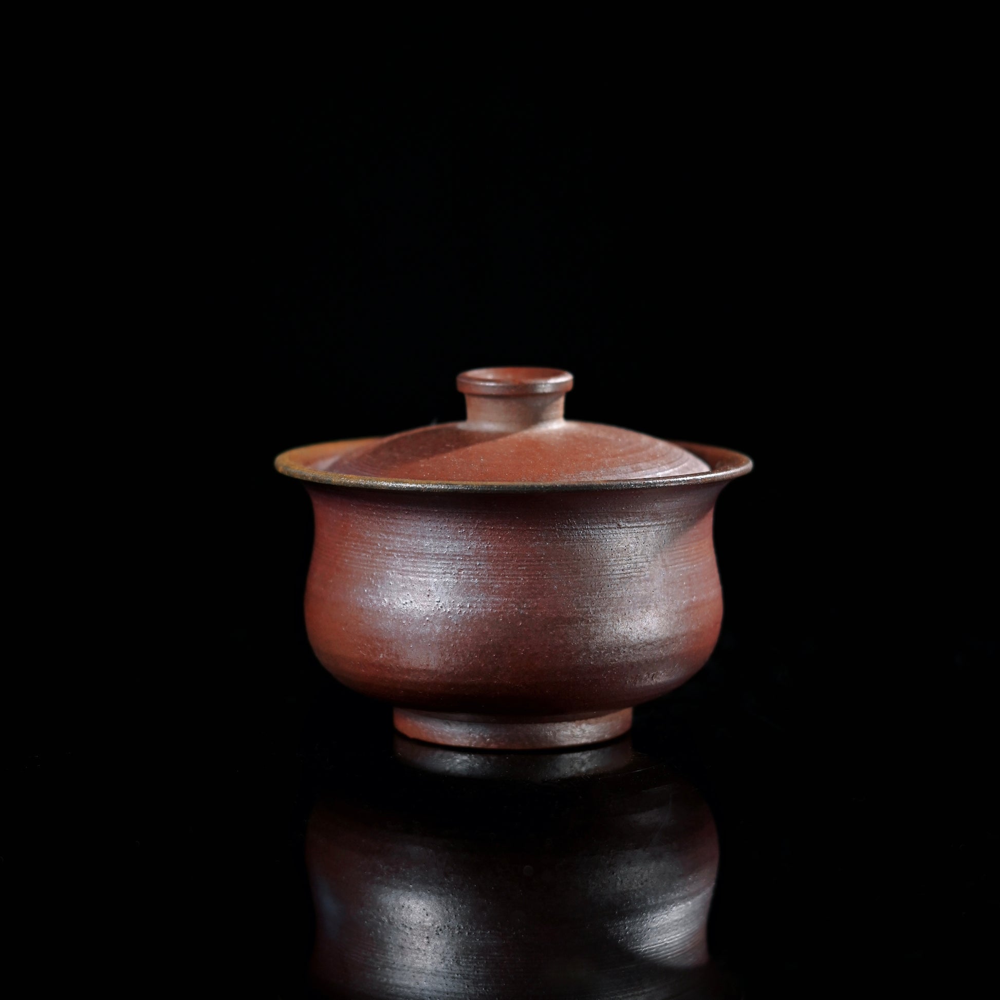 Wood-fired crimson lidded bowl showcasing rare uniform coloring achieved through controlled kiln atmosphere
