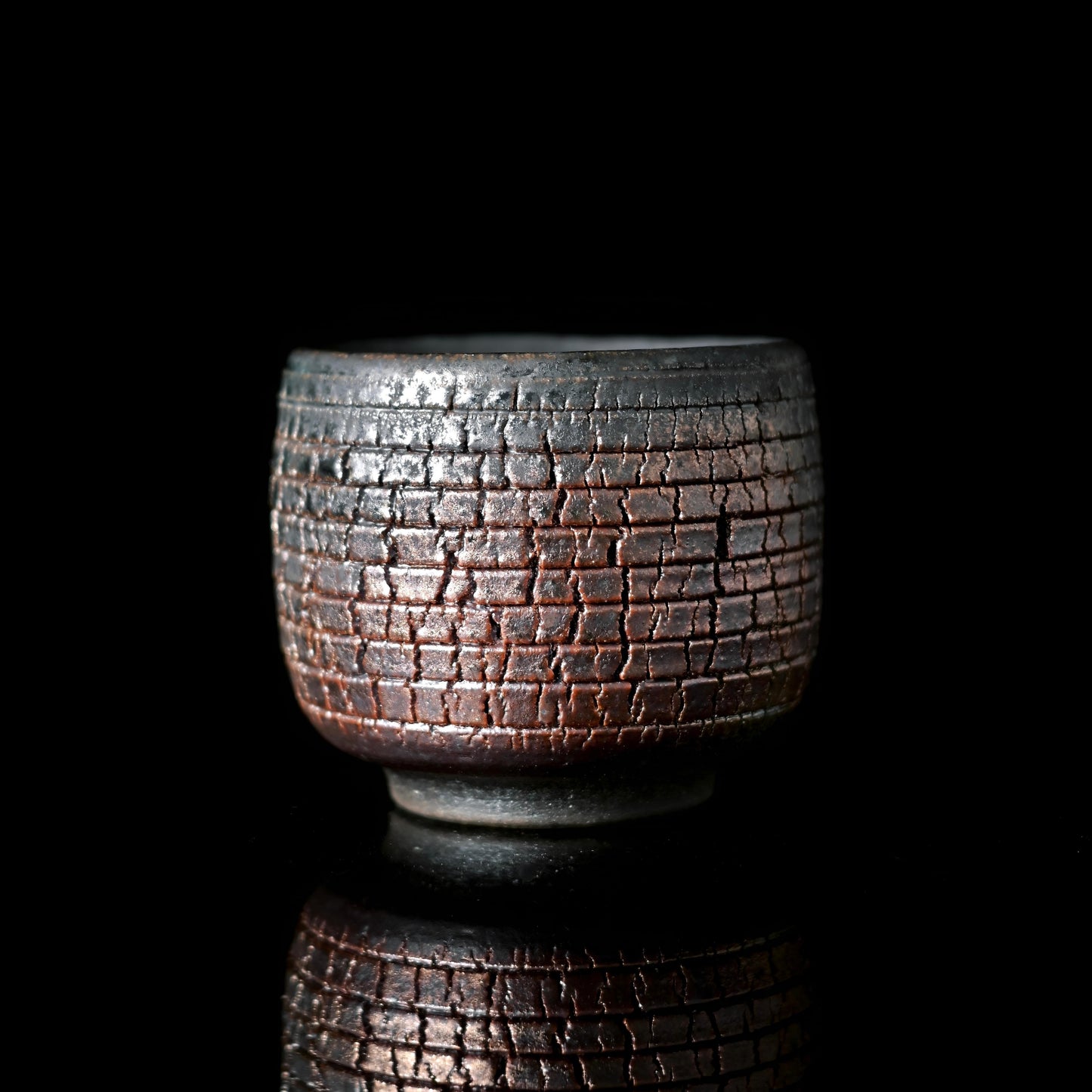 Handmade wood-fired iron-clay teacup with natural fire marks and textured surface