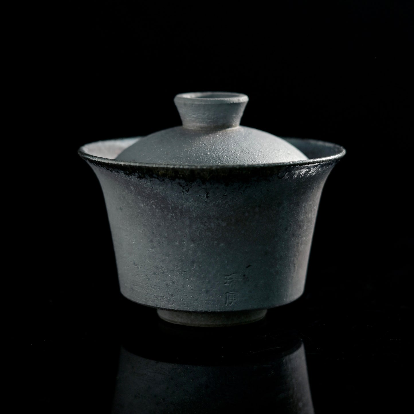 Handmade wood-fired lidded bowl showing unglazed clay body with natural ash markings