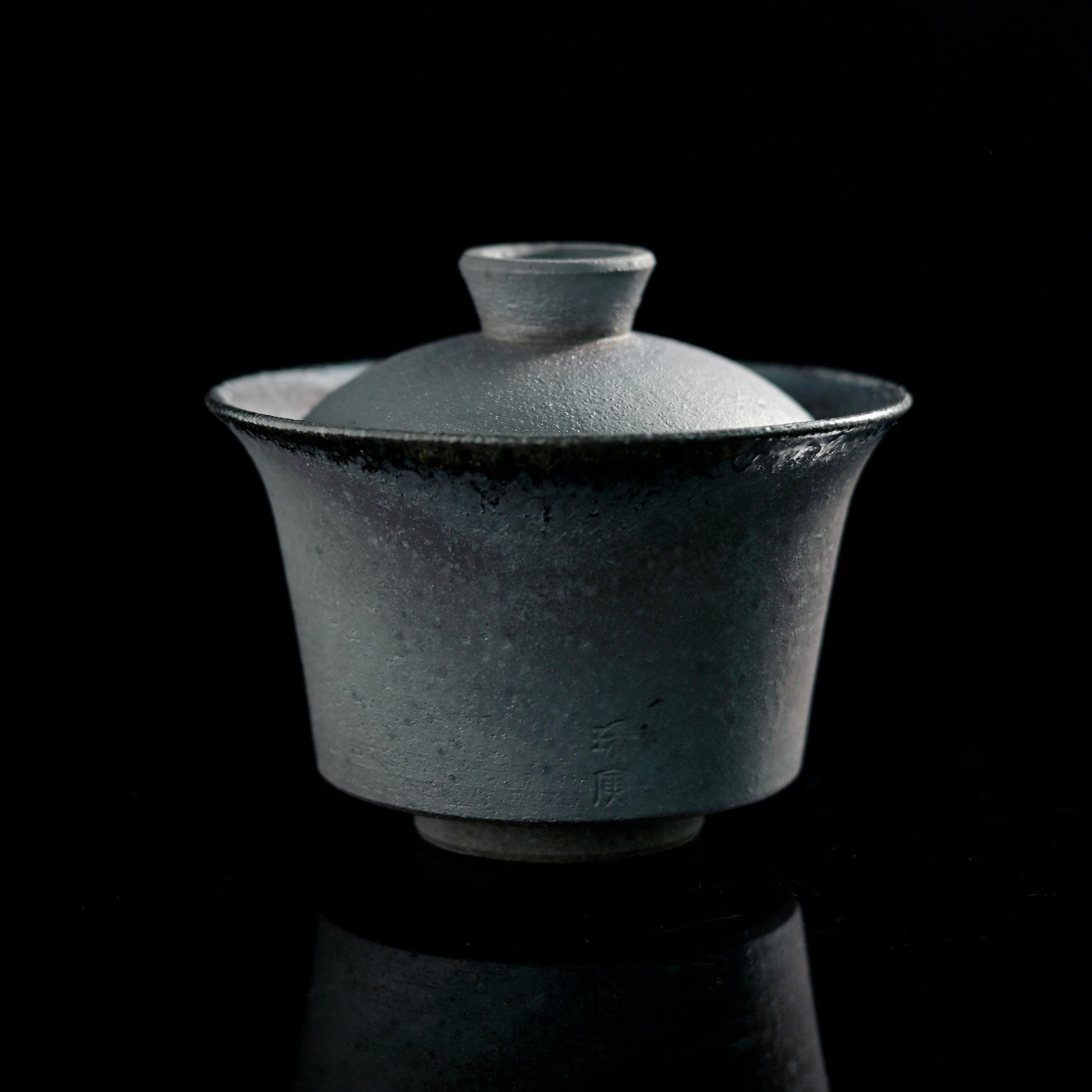 Handmade wood-fired lidded bowl showing unglazed clay body with natural ash markings
