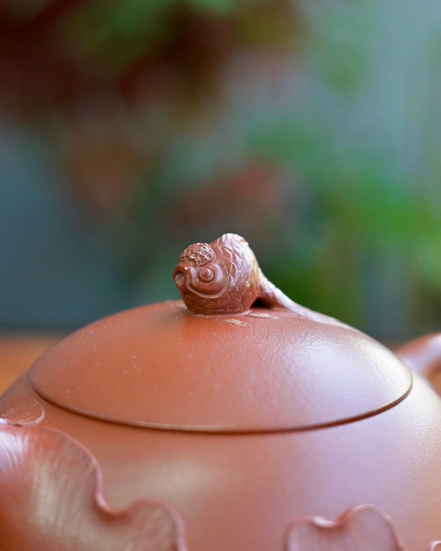 Carved lotus bas-relief rising from base upward, leaving upper third of teapot as bare clay