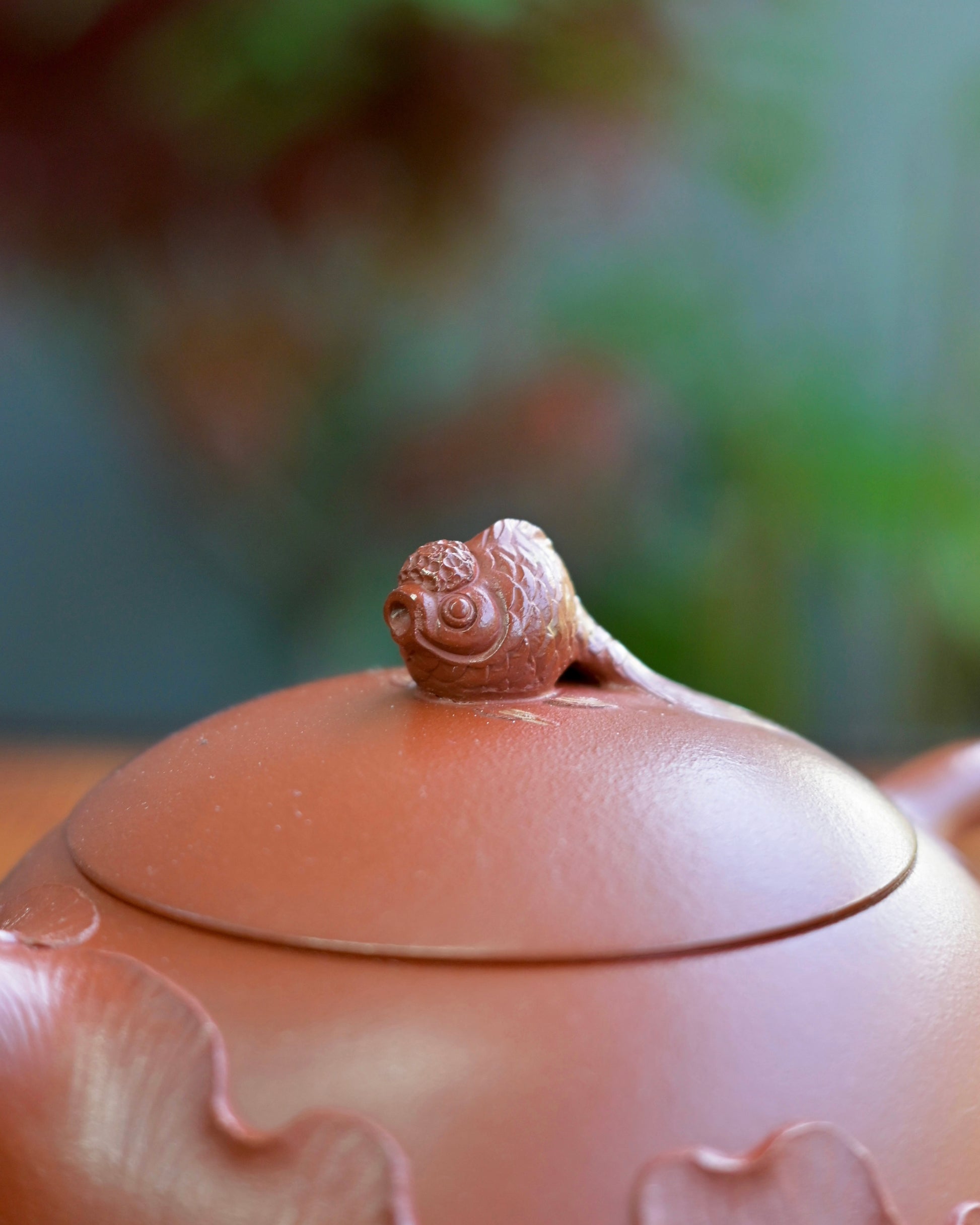 Carved lotus bas-relief rising from base upward, leaving upper third of teapot as bare clay