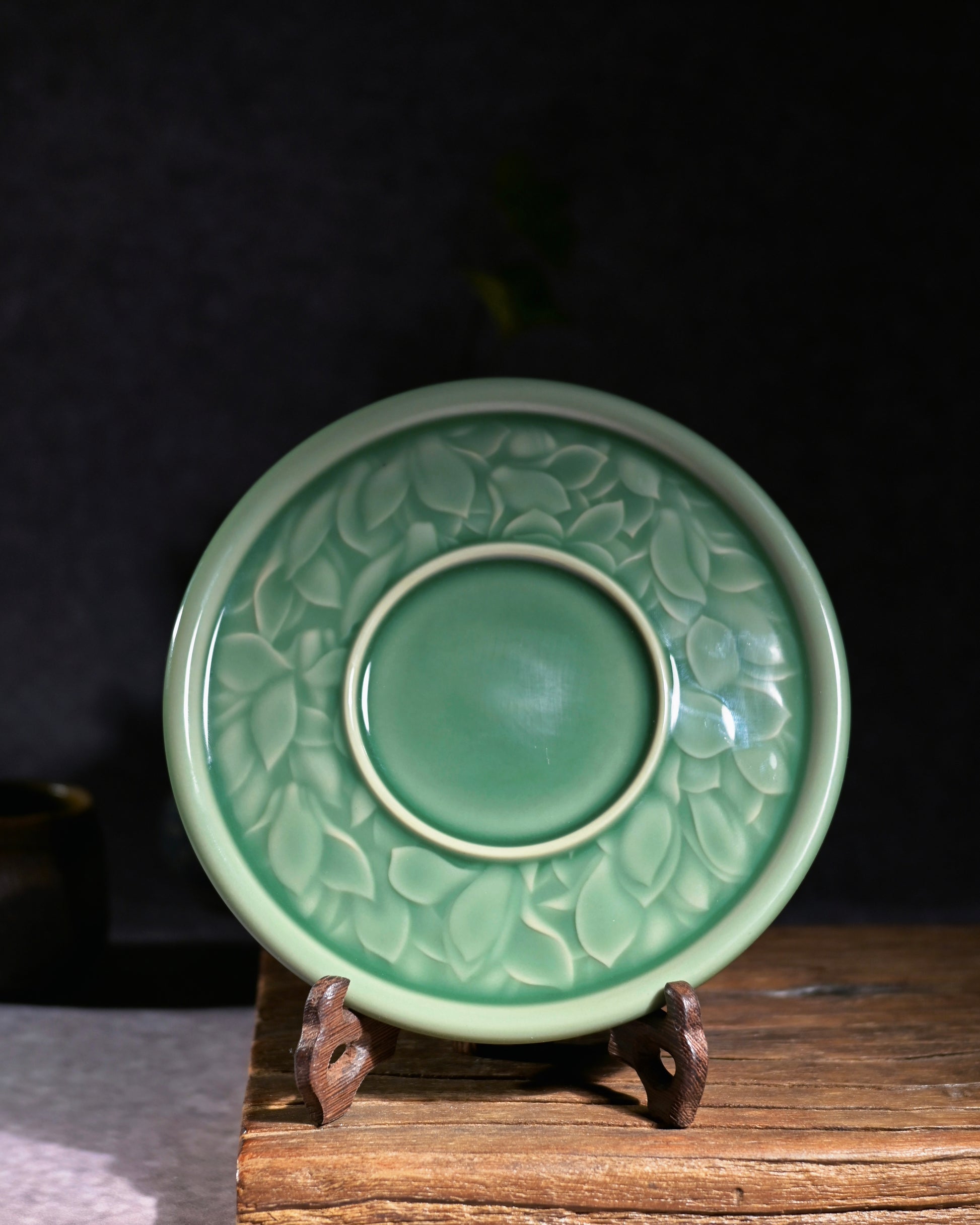 Zen style handmade Longquan tea saucer, magnolia engraved jade glaze teapot holder on wooden display rack