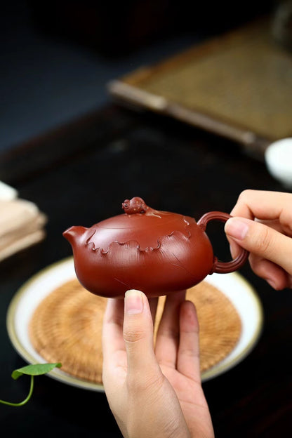 Pure zhuni clay Xishi teapot with exquisite hand-carved lotus design, showcasing Yixing's finest craftsmanship and hydrodynamically optimized pouring in a flattened silhouette.